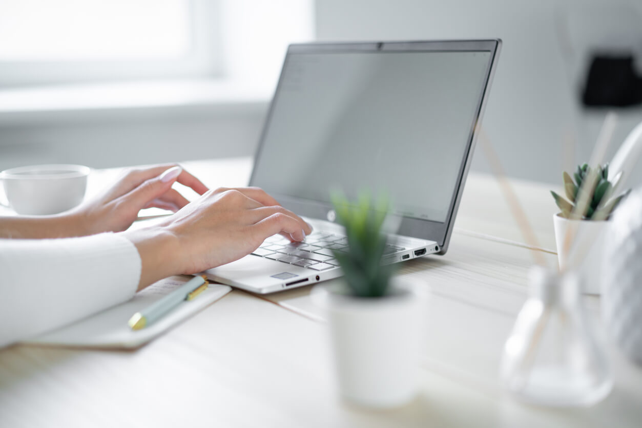 Woman typing on a laptop at a bright desk