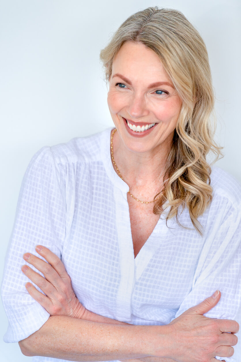 Smiling mature woman with arms crossed against a light background
