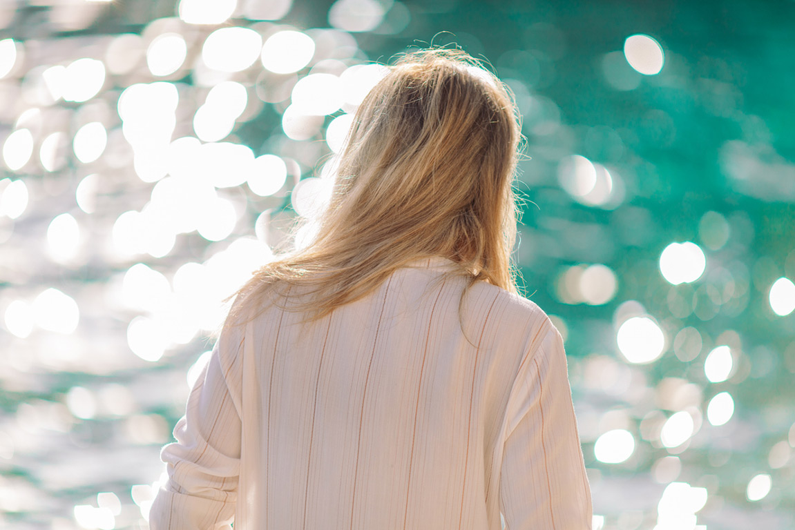 Woman reflecting by the water, navigating the realities of perimenopause symptoms